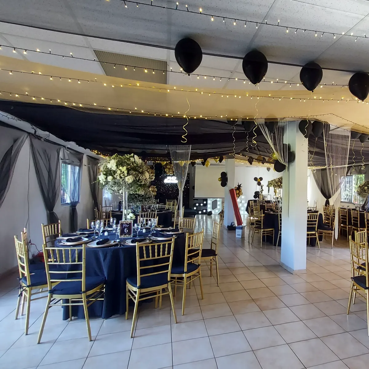 Salón decorado con mesas elegantes, luces cálidas y ambientación para evento formal en Espacio Mater